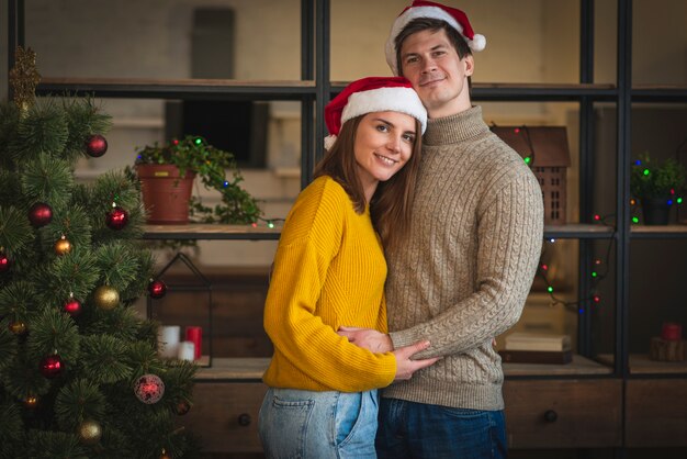 Pareja de tiro medio con sombreros de santa abrazándose