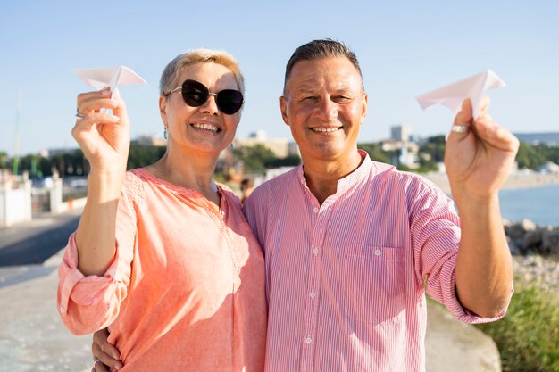 Pareja de tiro medio sosteniendo aviones de papel