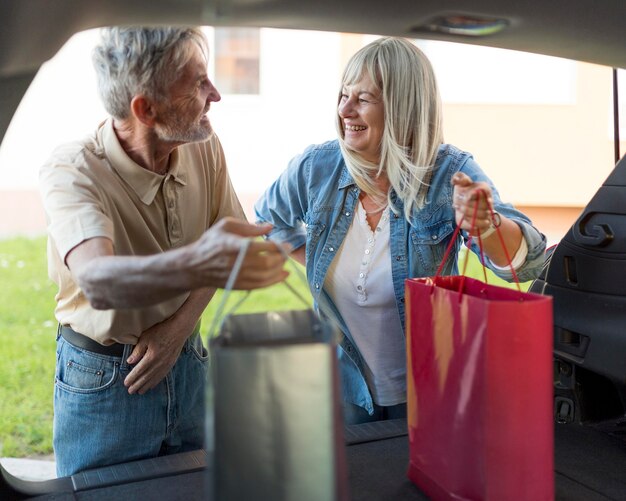 Pareja de tiro medio sosteniendo bolsas de la compra.