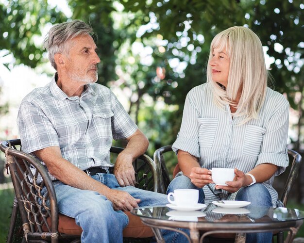 Pareja de tiro medio tomando café fuera