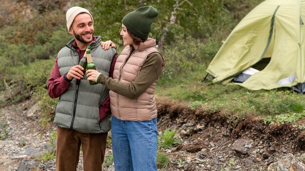 Pareja de tiro medio tomando una copa en la naturaleza