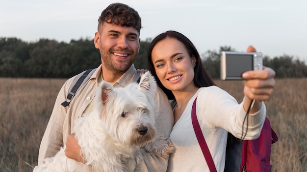 Pareja de tiro medio tomando selfie con perro