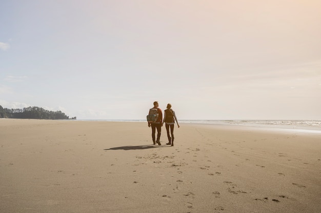 Pareja tomados de la mano y caminando en la playa