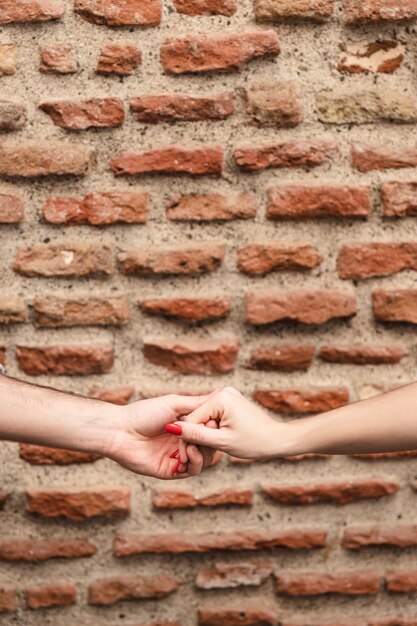 Pareja tomados de la mano contra la pared de ladrillo