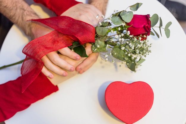 Pareja tomados de la mano en la mesa con rosa