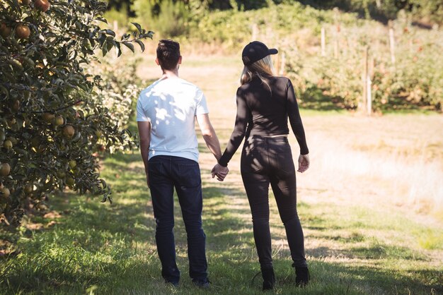 Pareja tomados de la mano y mirando el huerto de manzanas