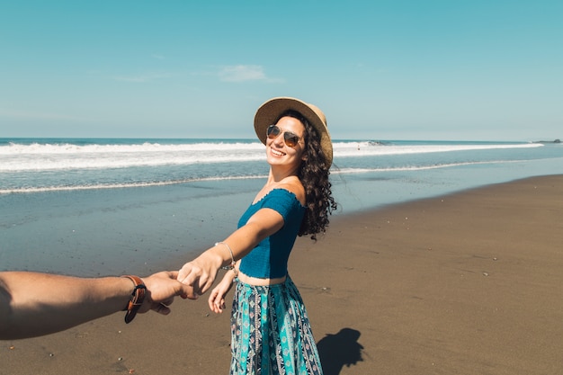 Pareja tomados de la mano de pie en la playa