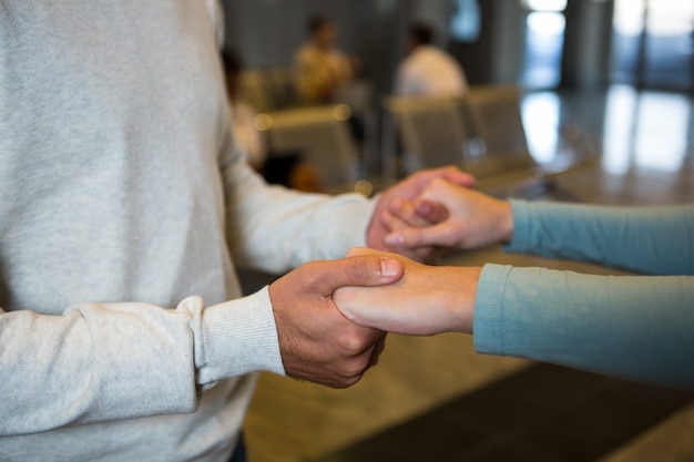 Pareja tomados de la mano en la sala de espera en la terminal del aeropuerto