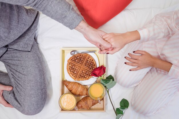 Foto gratuita pareja tomados de las manos sobre la bandeja con el desayuno