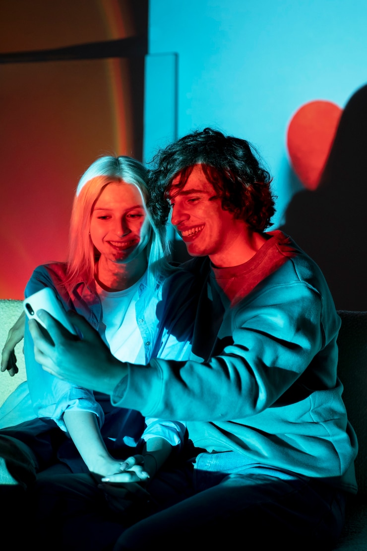 Foto gratuito pareja tomando fotos a la luz del proyector de películas
