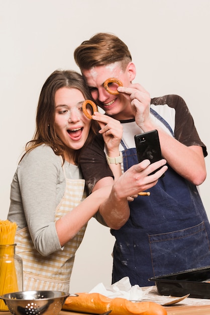 Foto gratuita pareja tomando selfie con galletas redondas cerca de los ojos