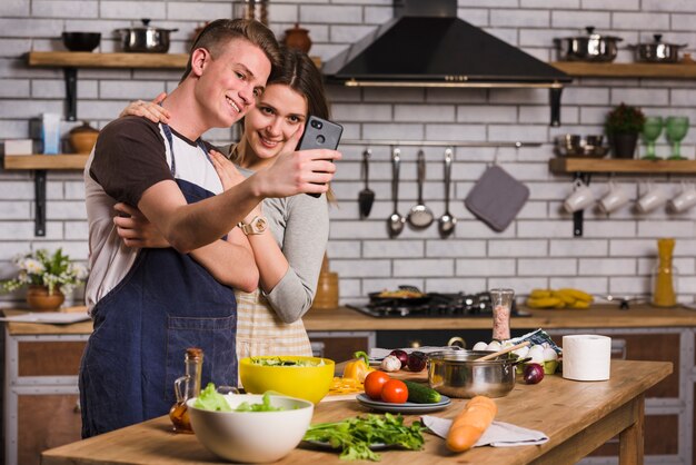 Pareja tomando selfie mientras cocina comida