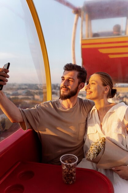 Pareja tomando selfie mientras están juntos en la rueda de la fortuna