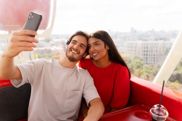 Pareja tomando selfie mientras están juntos en la rueda de la fortuna