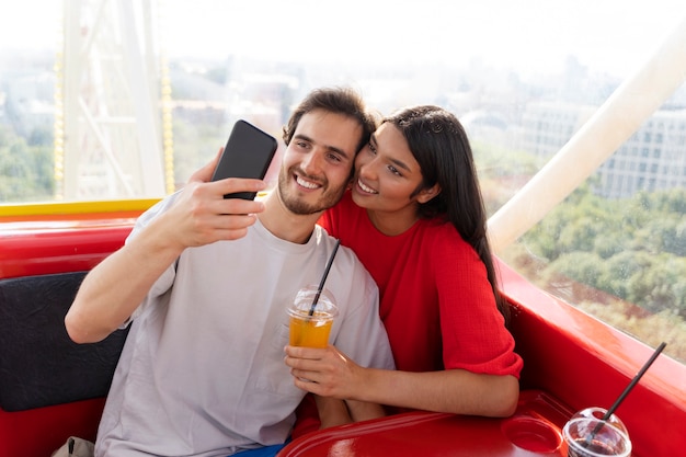 Pareja tomando selfie mientras están juntos en la rueda de la fortuna