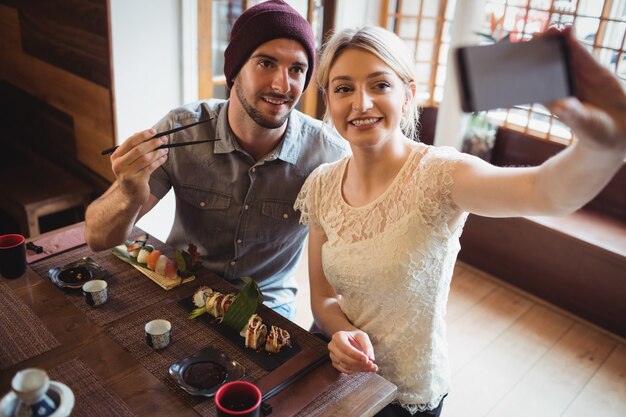 Pareja tomando selfie mientras sushi