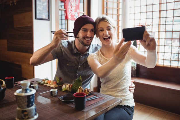 Pareja tomando selfie mientras sushi