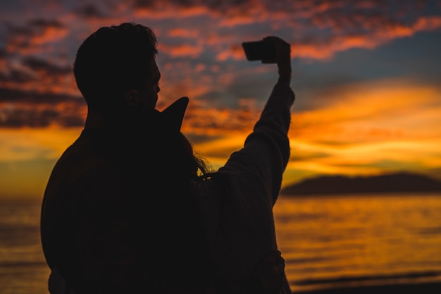 Pareja tomando selfie en la orilla del mar de noche