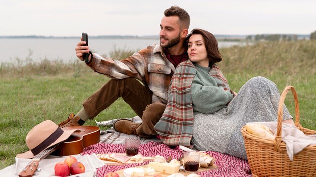 Pareja tomando selfie en picnic