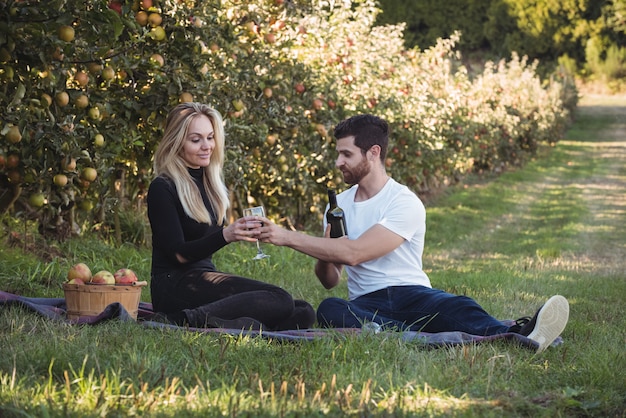 Pareja tomando vino en huerto de manzanas