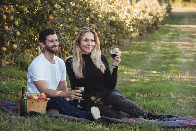 Pareja tomando vino en huerto de manzanas