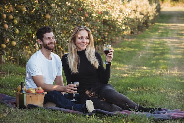 Pareja tomando vino en huerto de manzanas