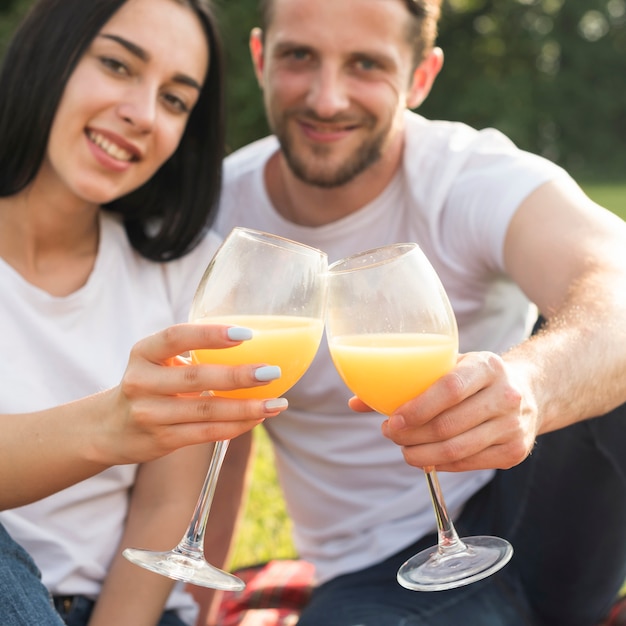 Pareja tomando zumo de naranja en manta de picnic