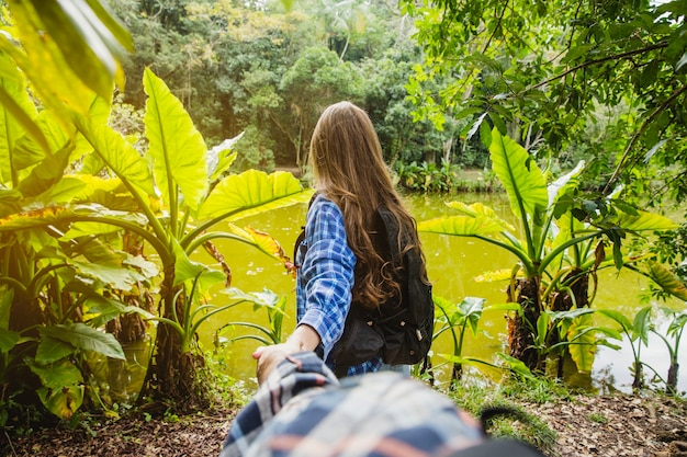 Foto gratuita pareja tomándose las manos y yendo hacia un bosque