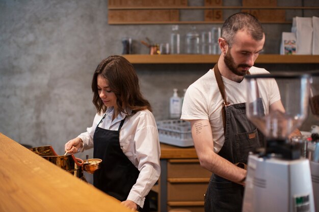 Pareja trabajando en la cafetería en delantales