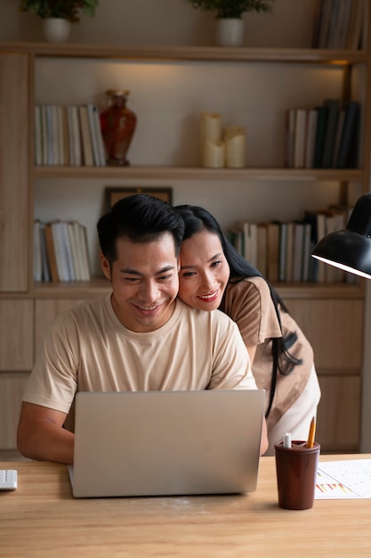 Pareja trabajando en casa en una laptop mientras es afectuosa