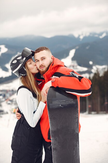 Pareja en trajes de snowboard. Deportistas en una montaña con una tabla de snowboard en las manos en el horizonte. Concepto de deportes