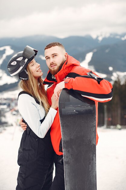 Pareja en trajes de snowboard. Deportistas en una montaña con una tabla de snowboard en las manos en el horizonte. Concepto de deportes