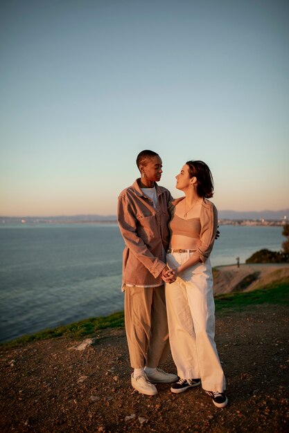 Pareja trans abrazándose al atardecer en la playa