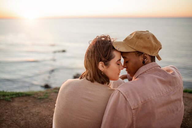 Pareja trans abrazándose en la playa al atardecer