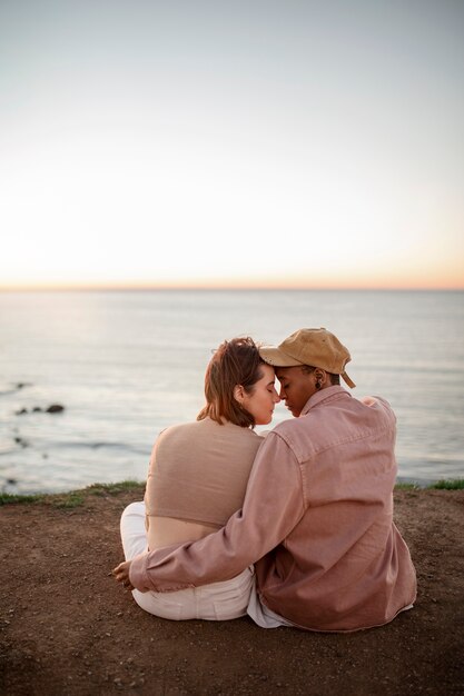 Pareja trans abrazándose en la playa al atardecer