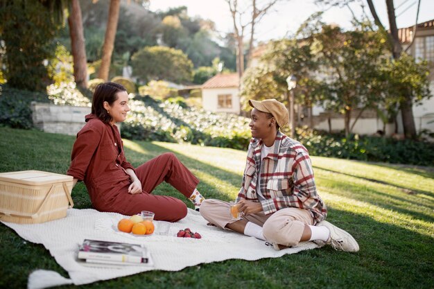 Pareja trans sonriendo mientras hace un picnic en el parque