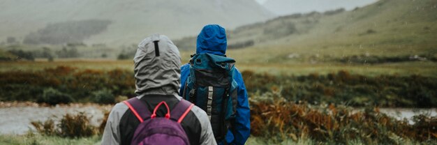 Pareja de trekking bajo la lluvia en las Tierras Altas