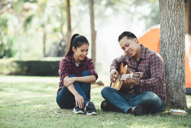 Pareja de turistas enamorados de tocar la guitarra en la naturaleza