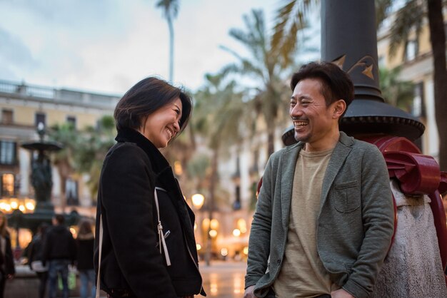 Pareja de turistas felices asiáticos hablando en una plaza