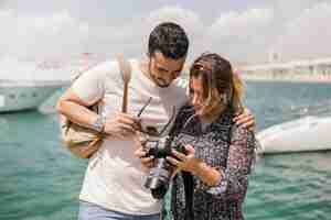 Foto gratuita pareja de turistas de pie cerca del mar mirando a la cámara