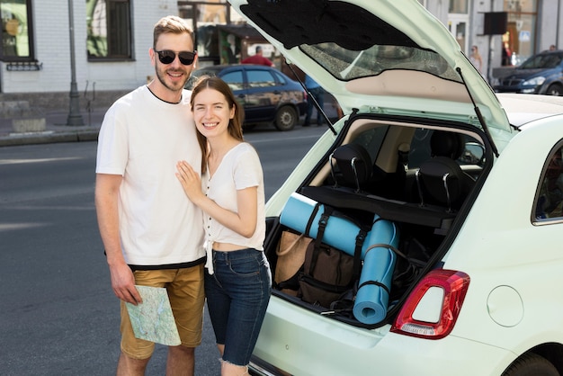 Pareja de turistas preparándose para salir de viaje con coche