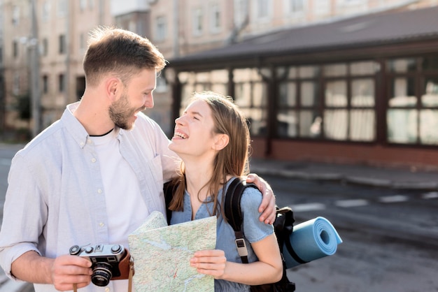 Pareja de turistas sonrientes al aire libre con mapa y cámara