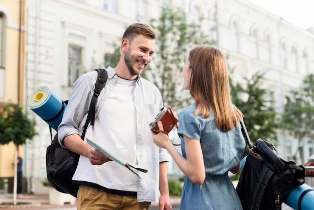 Foto gratuita pareja de turistas sonrientes con cámara y mapa