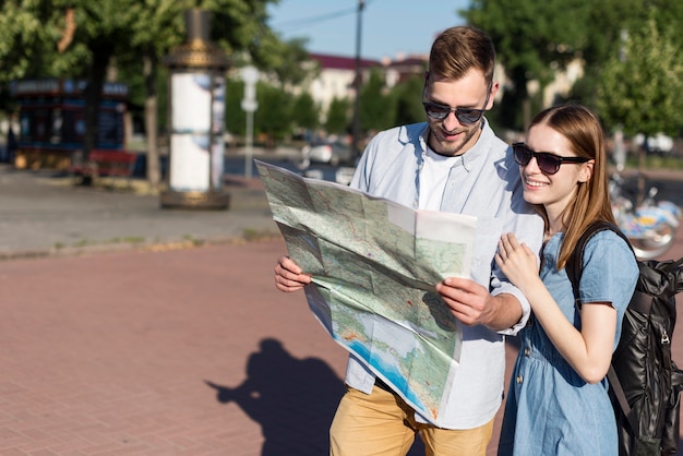 Foto gratuita pareja de turistas sonrientes mirando el mapa juntos