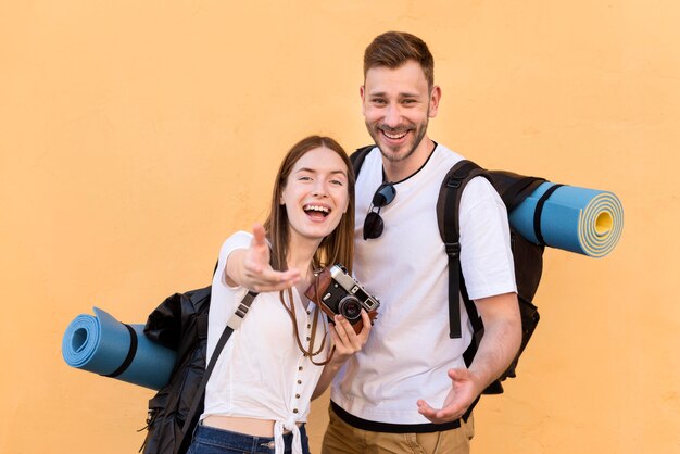 Pareja de turistas sonrientes con mochilas y cámara