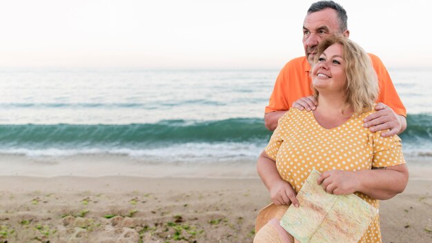 Pareja de turistas sonrientes posando en la playa