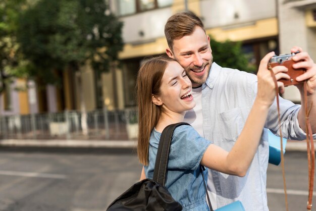 Pareja de turistas sonrientes tomando selfie con cámara