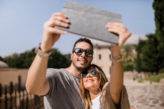 Pareja de turistas tomando selfie en tableta digital