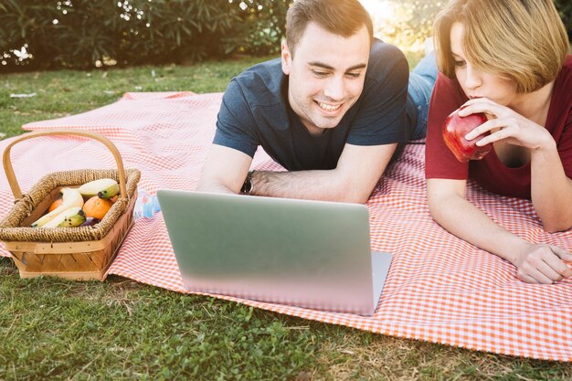 Pareja usando laptop en picnic