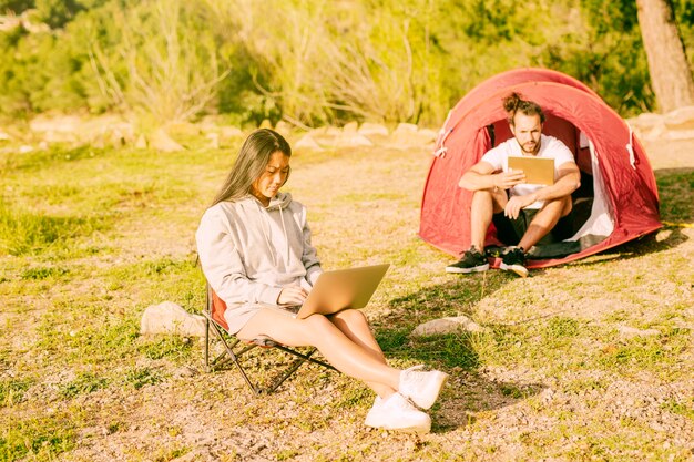 Pareja usando laptop y tableta trabajando al aire libre